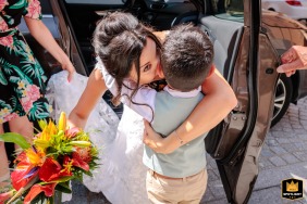 A documentary style photographer captures a tender moment in Montauban, France. The image shows a bride lovingly embracing her son outside of a church, a warm shot of joy and affection.
